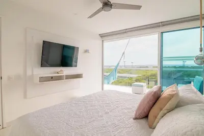 a white bedroom with a bed and a large window at TU CASA EN MORROS 3 in Cartagena de Indias