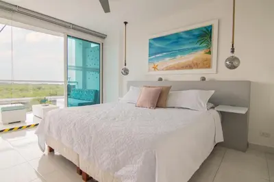 a white bedroom with a bed and a large window at TU CASA EN MORROS 3 in Cartagena de Indias