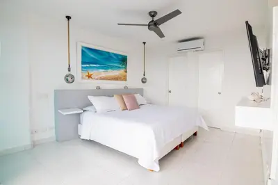 a white bedroom with a bed and a ceiling fan at TU CASA EN MORROS 3 in Cartagena de Indias