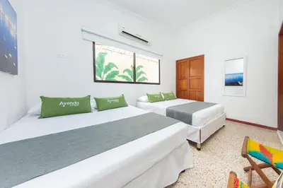 a bedroom with two beds and a chair at Hotel Ayenda Casa Cano 1805 in Cartagena de Indias
