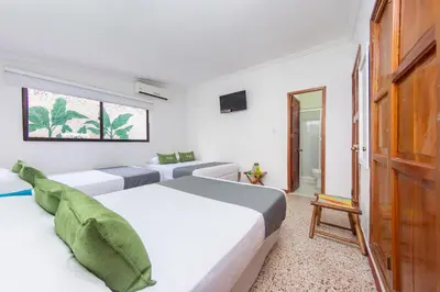 a white bedroom with two beds and a television at Hotel Ayenda Casa Cano 1805 in Cartagena de Indias