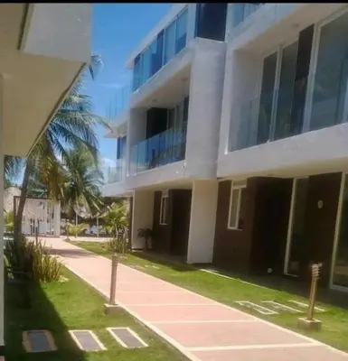 a large white building with a palm tree in front of it at Casa frente al mar con piscina in Coveñas