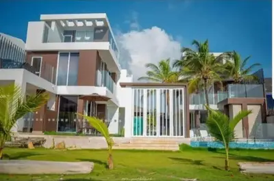 a large house with palm trees in front of it at Casa frente al mar con piscina in Coveñas