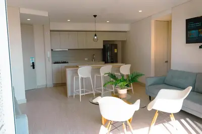 a kitchen and living room with white chairs and a couch at Confortable y exclusivo apartamento en Martinique Cielo Mar in Cartagena de Indias