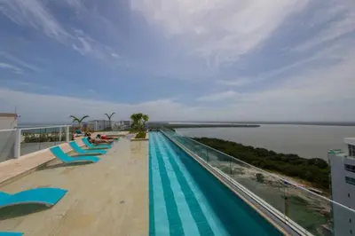 a swimming pool with blue chairs on a building at Confortable y exclusivo apartamento en Martinique Cielo Mar in Cartagena de Indias