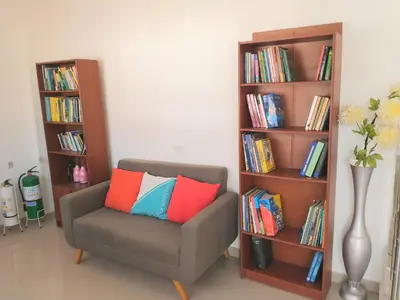 a chair with colorful pillows sitting next to a book shelf at CC House Cartagena in Cartagena de Indias