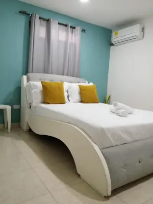 a bedroom with a white bed with yellow pillows at CC House Cartagena in Cartagena de Indias