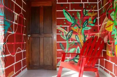 a red chair in front of a wall with a mural at Hostal La Guaca in Cartagena de Indias