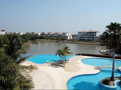 a resort with two pools with palm trees and a river at Condominio Campestre Laguna Club Cartagena in Los Arrayanes
