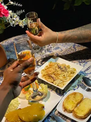 two people holding up glasses of wine and food on a table at Laguna Rosa Glamping in Coveñas
