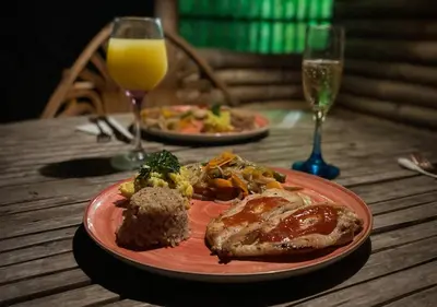 two plates of food on a table with glasses of orange juice at Laguna Rosa Glamping in Coveñas