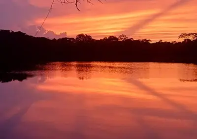 a view of a lake with a sunset in the background at Laguna Rosa Glamping in Coveñas