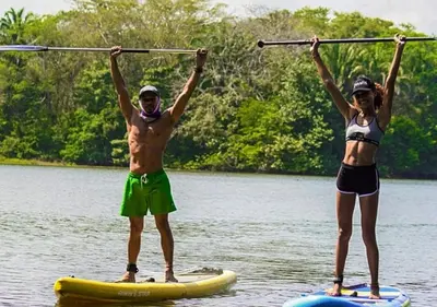 a man and a woman on paddle boards in the water at Laguna Rosa Glamping in Coveñas