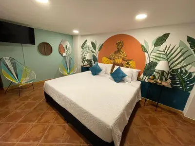 a bedroom with a bed with a painting on the wall at Candilejo Hotel Boutique in Cartagena de Indias