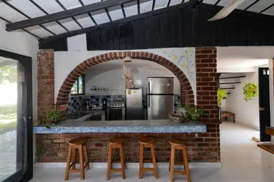 a kitchen with a brick wall and a counter with stools at Cabana Canaima in Coveñas