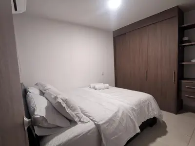 a bedroom with a white bed and a wooden cabinet at Hermoso Apartamento Zona Norte Miramar # in Barranquilla