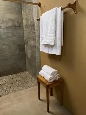 a bathroom with white towels and a stool with a shower at Casa Bustani Isla in Bocachica