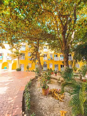 a yellow building with trees and plants in a courtyard at conjunto habitacional las bóvedas in Cartagena de Indias