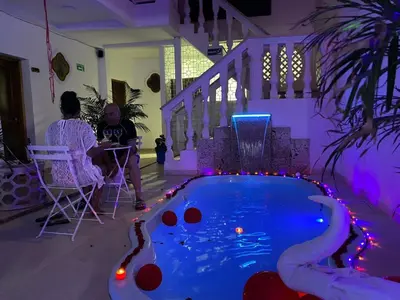 a woman sitting in a chair next to a swimming pool at Casa Gran Fuente in Cartagena de Indias