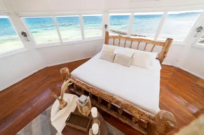 a bedroom with a bed with a view of the ocean at Quinta del Mar Crystal Beach in Tintipan Island