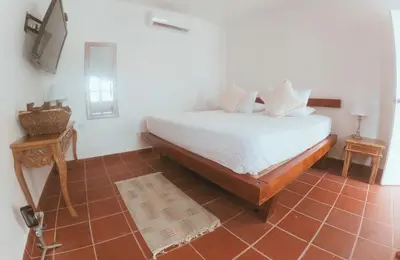 a bedroom with a bed with white sheets and a television at Quinta del Mar Crystal Beach in Tintipan Island