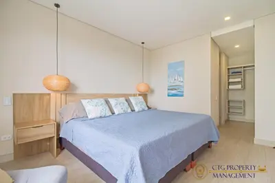 a bedroom with a bed with a blue comforter at Martinique Cartagena - Apartamentos A Corta Caminata De Playa Azul in Cartagena de Indias