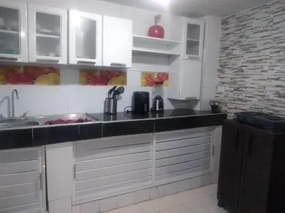 a kitchen with white cabinets and a black counter top at Encantadora casa con ambiente guajiro 2 in Barranquilla