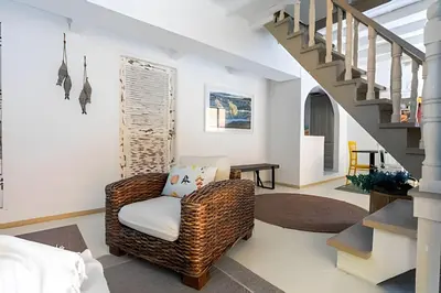 a living room with a wicker chair and stairs at Laurdhomes Historic Center Plaza SantoDomingo 3Bth in Cartagena de Indias