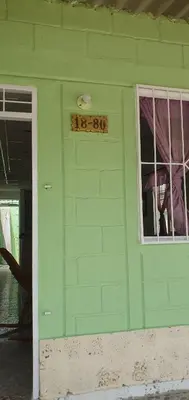 a green house with a sign in a window at Casa de descanso Cartagena-Turbaco in Turbaco