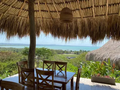 a table and chairs sitting under a straw umbrella at Hotel Bahia Rada in Moñitos