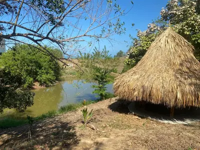 a grass hut next to a river with a lake at Hotel Bahia Rada in Moñitos