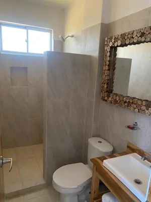 a bathroom with a toilet and a sink and a mirror at Hotel Bahia Rada in Moñitos