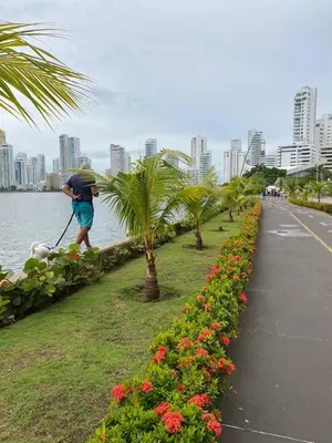 a man with an umbrella walking a sidewalk next to the water at Lujoso Apartamento en Bocagrande in Cartagena de Indias