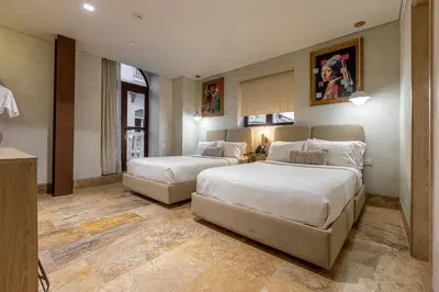 a hotel room with two beds and a table at Hotel Voilá Centro Histórico in Cartagena de Indias