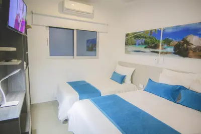 two beds in a hotel room with a tv at Hotel Poblado Coveñas in Coveñas