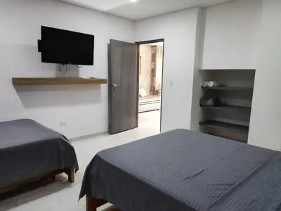 a bedroom with two beds and a flat screen tv at zara's apartamento en coveñas in Coveñas