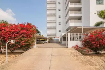 a walkway in front of a building with red flowers at Apartamento con balcon y vista al mar en Coveñas in Coveñas
