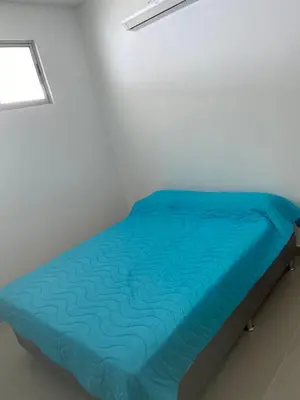 a bed with a blue comforter in a room at Apartamento con balcon y vista al mar en Coveñas in Coveñas