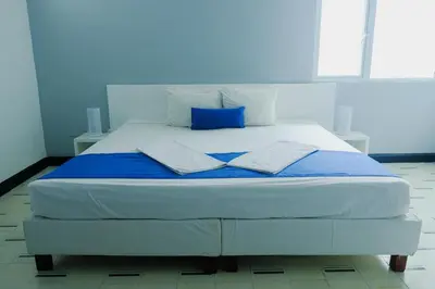 a white bed with blue sheets and pillows on it at Eslait Hotel & Apartamentos in Barranquilla