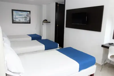 two beds in a room with a tv and a bed sidx sidx sidx at Eslait Hotel & Apartamentos in Barranquilla