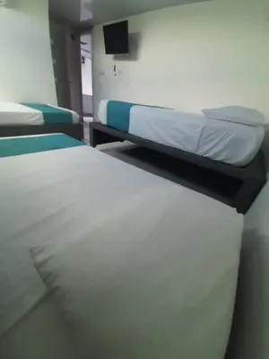 a room with two beds and a tv on a wall at Sky view hotel tolu in Tolú