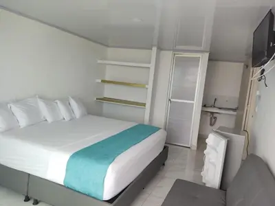 a bedroom with a white bed and a television at Sky view hotel tolu in Tolú