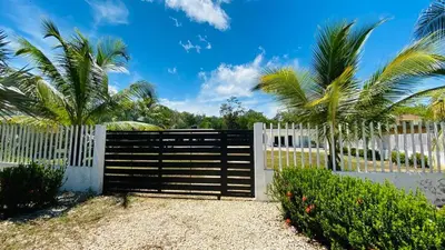 a white fence with palm trees behind it at Cabaña pescador de colores in Coveñas