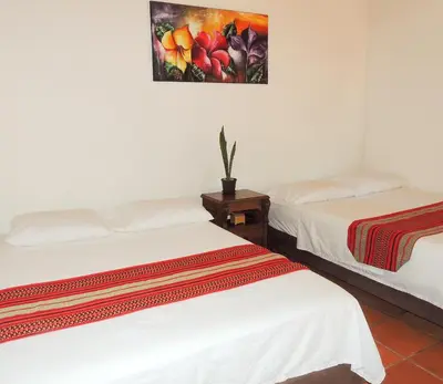 two beds in a room with a painting on the wall at Portoazul Casa de Playa in Puerto Colombia