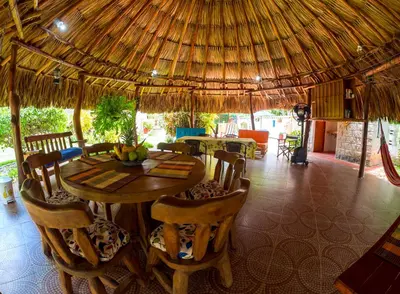 a dining room with a table and a straw umbrella at Portoazul Casa de Playa in Puerto Colombia