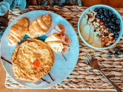 a plate of food with an omelet and a bowl of fruit at Hotel Prana Beach in Baru