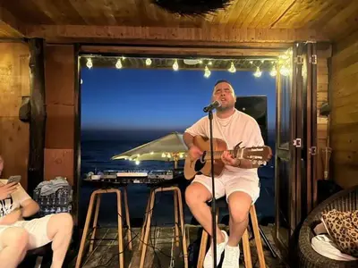 a man sitting in a bar playing a guitar at Hotel Prana Beach in Baru