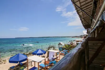 a beach with chairs and umbrellas and the ocean at Cabaña Coral Azul in Playa Blanca