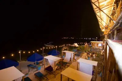a group of tables and umbrellas on a beach at night at Cabaña Coral Azul in Playa Blanca
