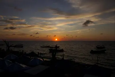 a sunset over the ocean with boats in the water at Cabaña Coral Azul in Playa Blanca